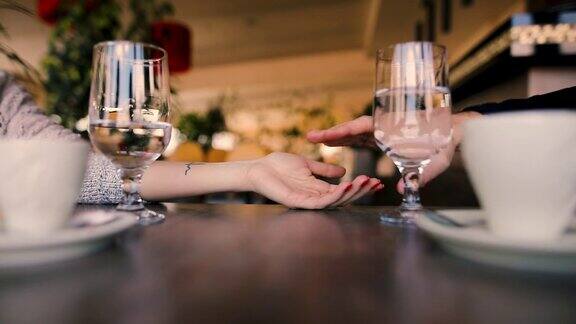 在一个约会之夜坐在餐厅里的年轻夫妇手牵着手