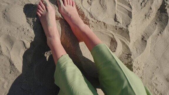 一个不认识的女人在沙滩上玩脚