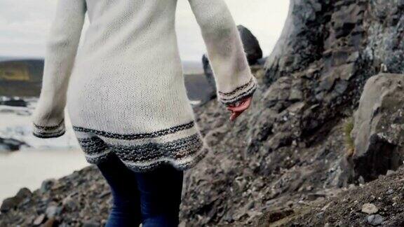 年轻的女游客徒步旅行在山脉通过岩石附近的瓦特纳冰川泻湖在冰岛