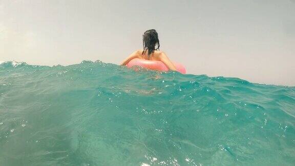 海浪一个女人在海里的一个充气圈上游泳