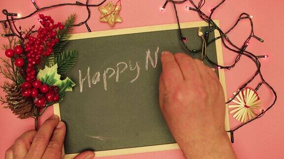 一个男性用粉笔在黑色的写字板上写着新年快乐