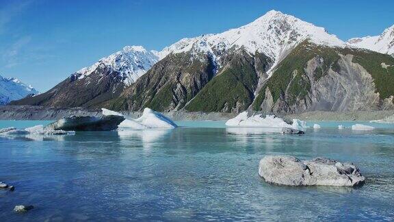 冰山漂浮在冰川泻湖与雪山的背景