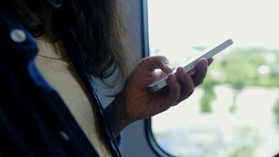 一名年轻女子在火车上浏览智能手机