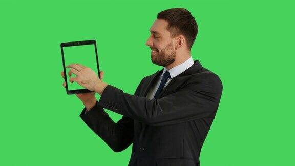 中景一个英俊的商人拿着平板电脑与另一只手做滑动触摸手势平板电脑和背景都是绿屏