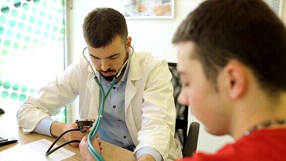 年轻男医生用医疗仪器测量病人的血压