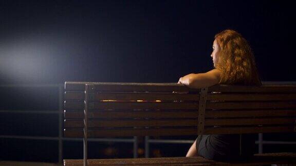 晚上坐在城市长椅上看海的女人