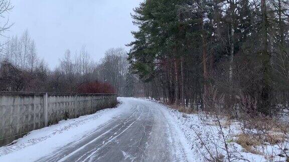 俄罗斯的冬天暴风雪清洁工在冬天的森林里扫过柏油路下雪了松林《暮光之城》4K60fps