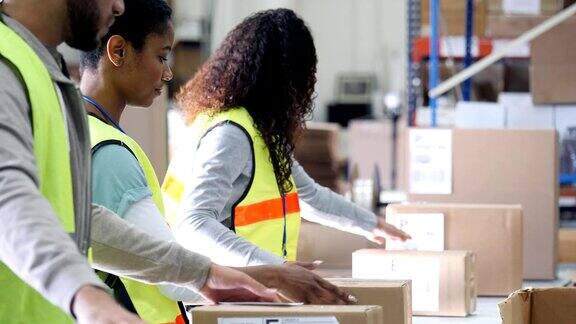 一群年轻的配送仓库工人在寄出包裹前会检查包裹