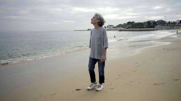 笑容可掬的白发苍苍的老妇人在海边散步