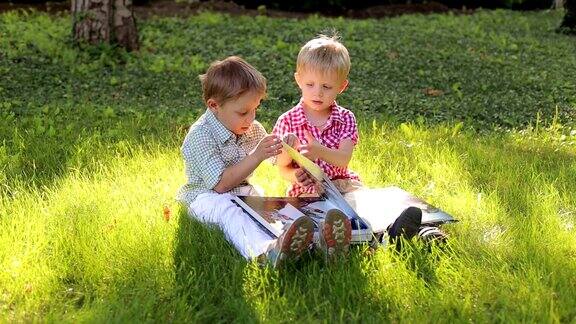 两个小男孩拿着相册在公园里