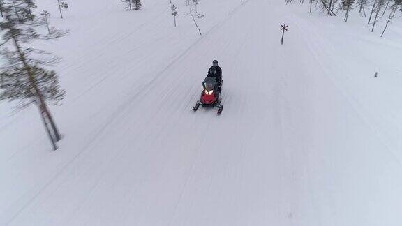 空中拍摄特写:一对夫妇在冬天的雪地上骑着雪地车