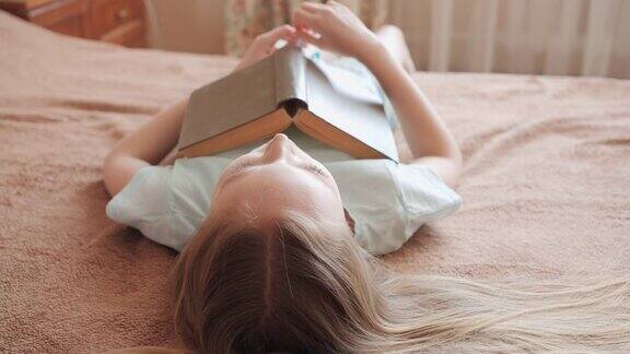 笑着的女孩躺在床上拿着书