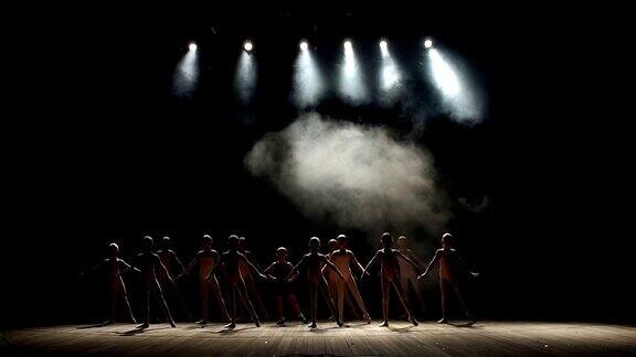 一群孩子在黑暗中在舞台上跳芭蕾舞