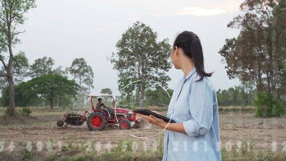 未来主义的亚洲女性农民在农田里使用便携式平板电脑