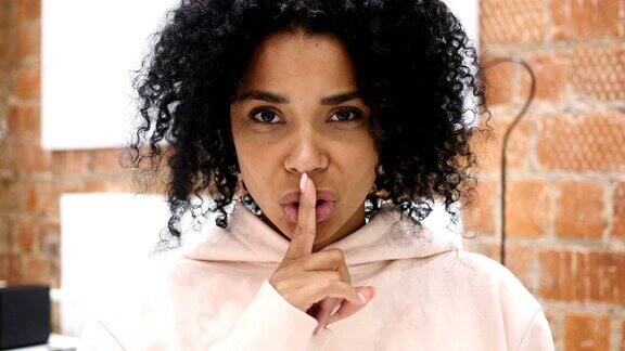 非裔美国妇女沉默的肖像手指放在嘴唇上室内