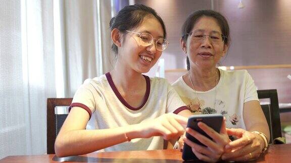 亚洲家庭年轻的青少年和母亲度假放松使用数字平板电脑和智能手机在家里做作业放松与在线游戏和在社交网络上的短信