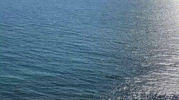 美丽的绿松石银色海景波光粼粼的清澈海水海水表面的波浪在阳光下闪闪发光阳光照射在海浪上的刺眼光芒