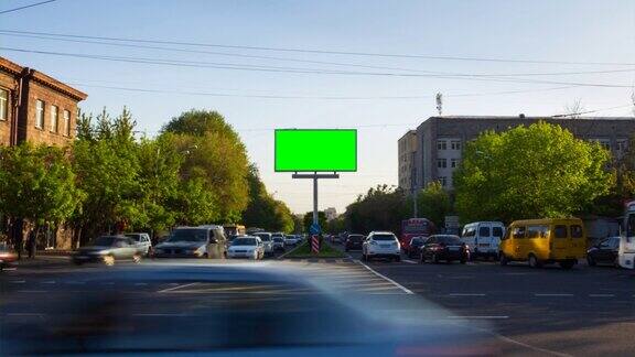 4K时间推移视频一个绿色屏幕的广告牌背景是城市交通汽车行人树木蓝天