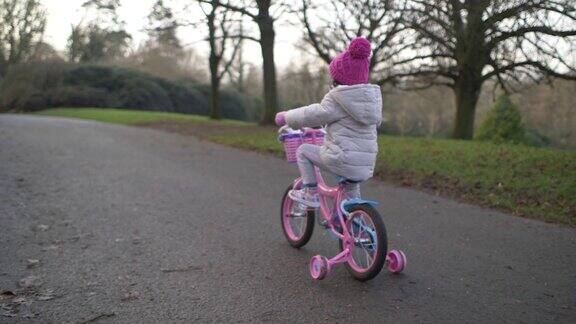 北爱尔兰冬季乡村公园里骑自行车的小女孩