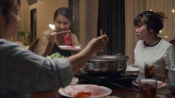 晚上一群快乐的亚洲朋友在家里吃着火锅聚在一起吃春节团圆饭生活方式享受美食