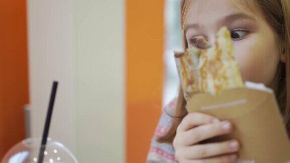 一个小女孩在咖啡馆里吃着煎饼喝着鸡尾酒