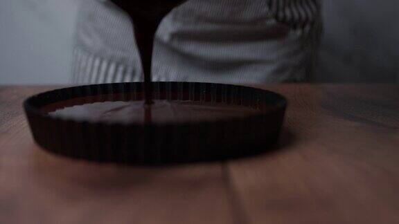 将优质黑巧克力液体从平底锅倒入专业的不粘锅中准备好巧克力蛋糕的饼干底座
