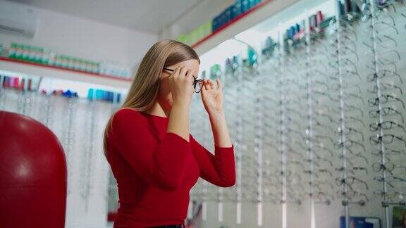 在眼镜店选购眼镜的美女年轻的买手正在试新的眼镜视力