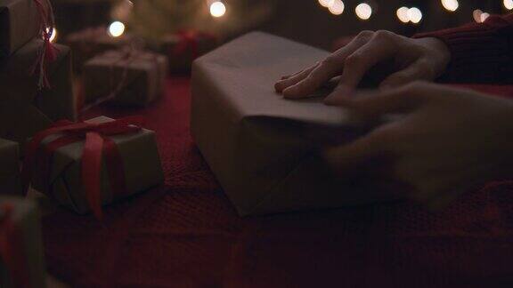 女人包装礼物盒与牛皮纸在家里的桌子为圣诞节