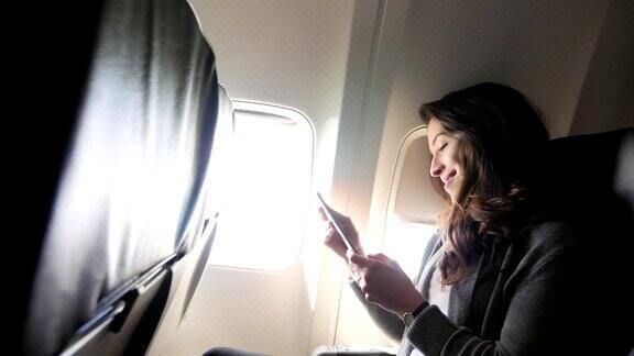 一名年轻女子在飞行中使用智能手机时大笑