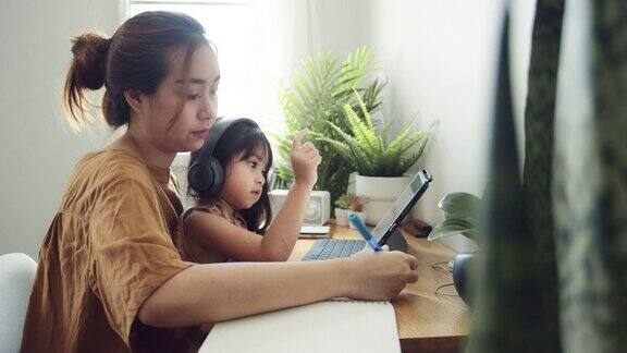 亚裔女儿在家和母亲一起参加网络课程