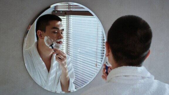 日本男子站在浴室镜子前刮脸