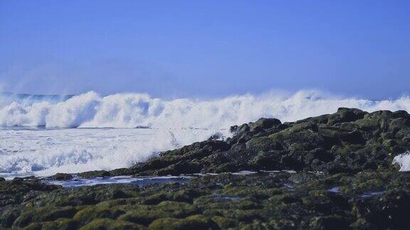 多岩石的海岸线对比泡沫的波浪和绿松石般的水