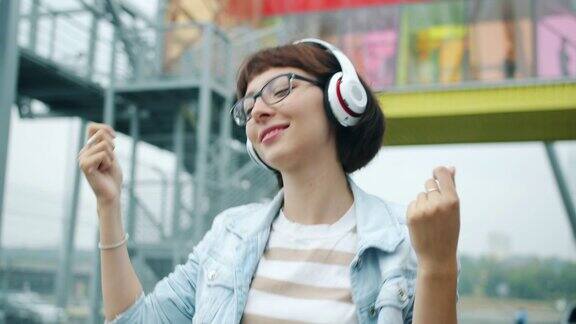 快乐的女人听音乐戴着耳机在户外跳舞的肖像