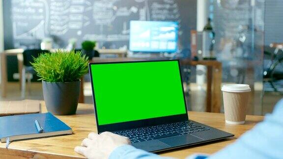 办公桌前正在使用绿色屏幕的笔记本电脑
