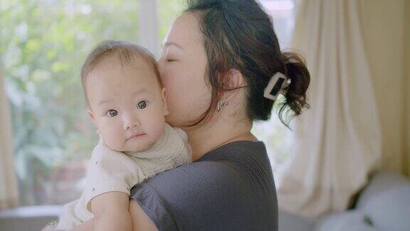 近距离肖像年轻妈妈抱抱抱抱小女婴可爱的小婴儿学步可爱的亚洲妈妈抱抱小婴儿孩子放松享受温柔的家庭时刻母性概念