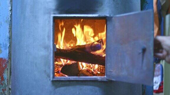 手打开壁炉门家里烧木头的炉子就被加热了原木躺在燃木的火炉里红色的火焰一个舒适的家4kProRes
