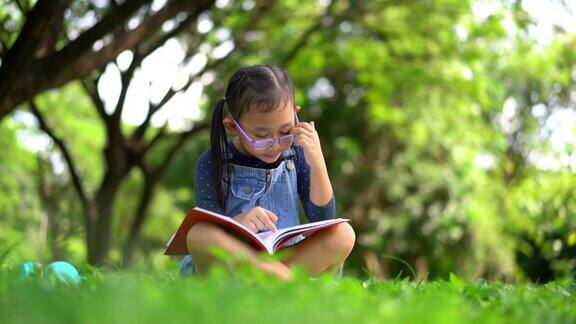 快乐的亚洲小女孩在花园里看书