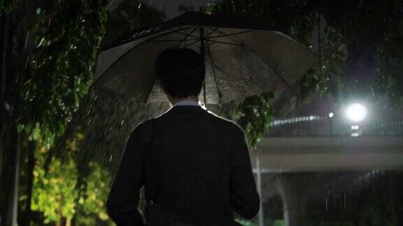 亚洲商人在雨中打伞