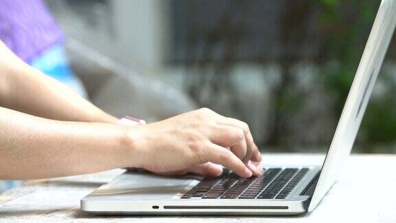 女性用手在笔记本电脑键盘上打字