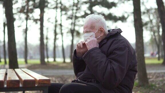 老人独自坐在公园里戴着防护口罩