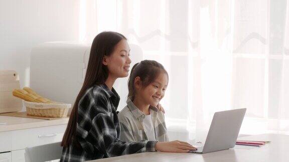 亚洲母亲教女儿在家使用笔记本电脑