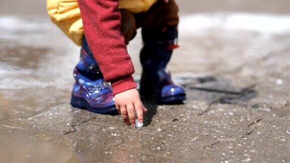 一个蹒跚学步的小男孩喜欢在春日的水坑里玩耍