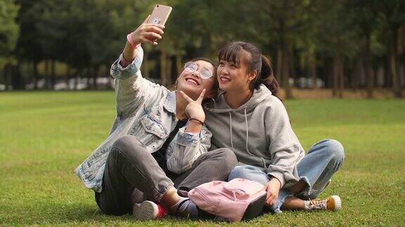 两个亚洲大学女孩使用手机在校园自拍