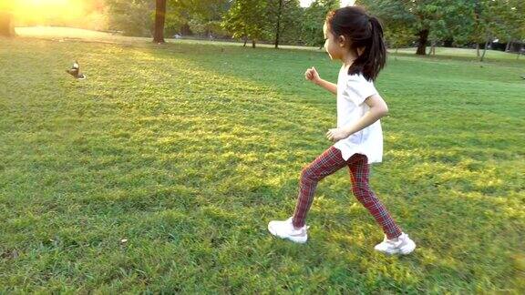 快乐亚洲小女孩在公园里跑去抓鸟