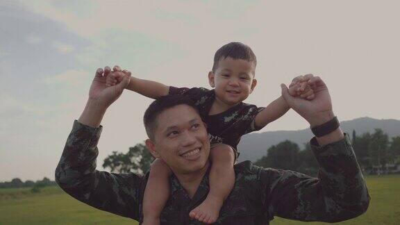 士兵父亲抱着他的儿子在公园里玩耍