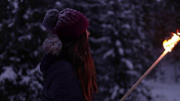 十几岁的女孩和她的家人拿着火把在冬天的森林里散步