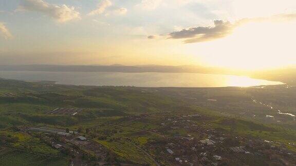在以色列北部戈兰高地和泰伯利亚上空拍摄的日落加利利海或约旦河谷的Kinnert上有着桔黄色风景的开阔田野和山脉