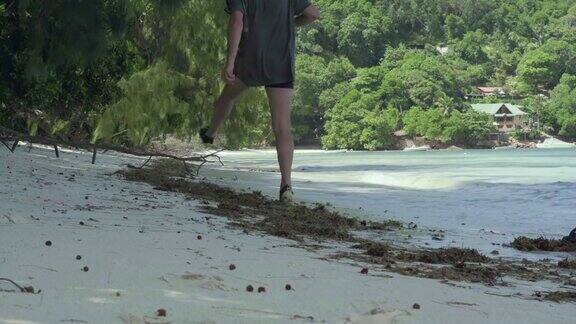 一个成年男子走在一个有着棕榈树的小岛的海滩上
