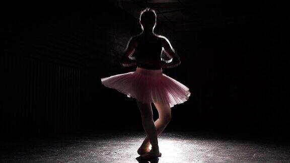 美丽的剪影年轻芭蕾舞女演员的尖鞋在黑色混凝土地板的背景芭蕾舞练习美丽苗条的身材的芭蕾舞者缓慢的运动
