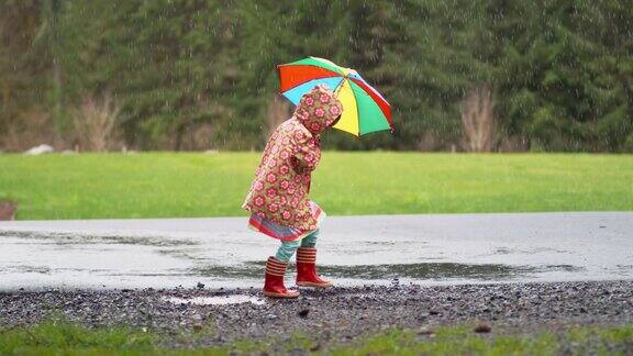 小女孩撑着伞在雨中嬉戏慢镜头
